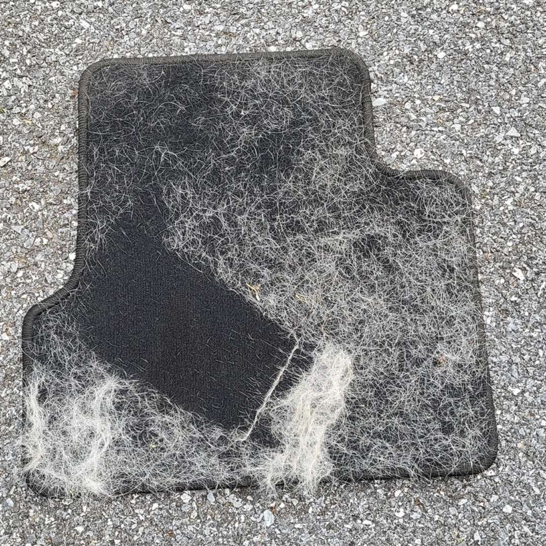 Car floor mat half cleaned of pet hair