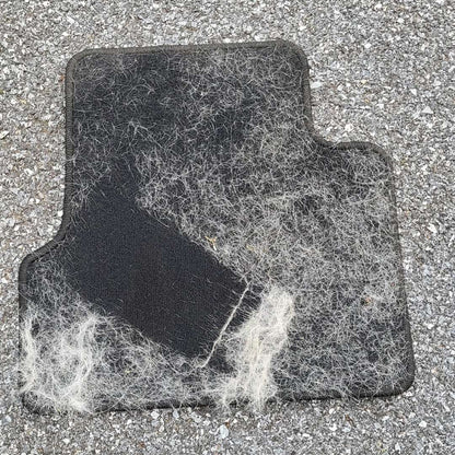 Car floor mat half cleaned of pet hair